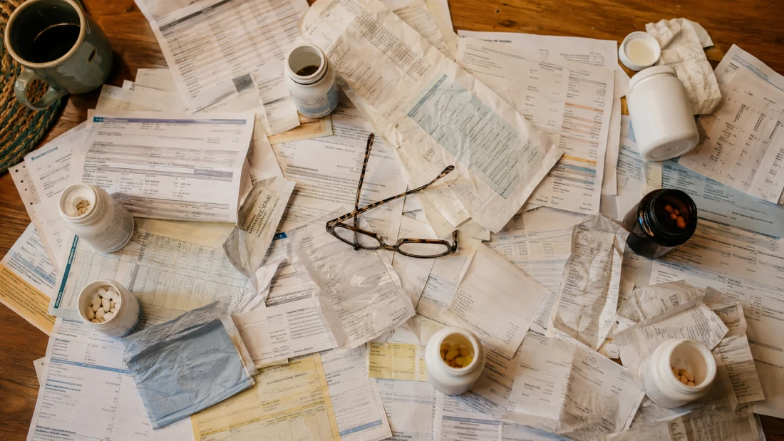 Medical bills, supplement bottles, and receipts scattered across a table